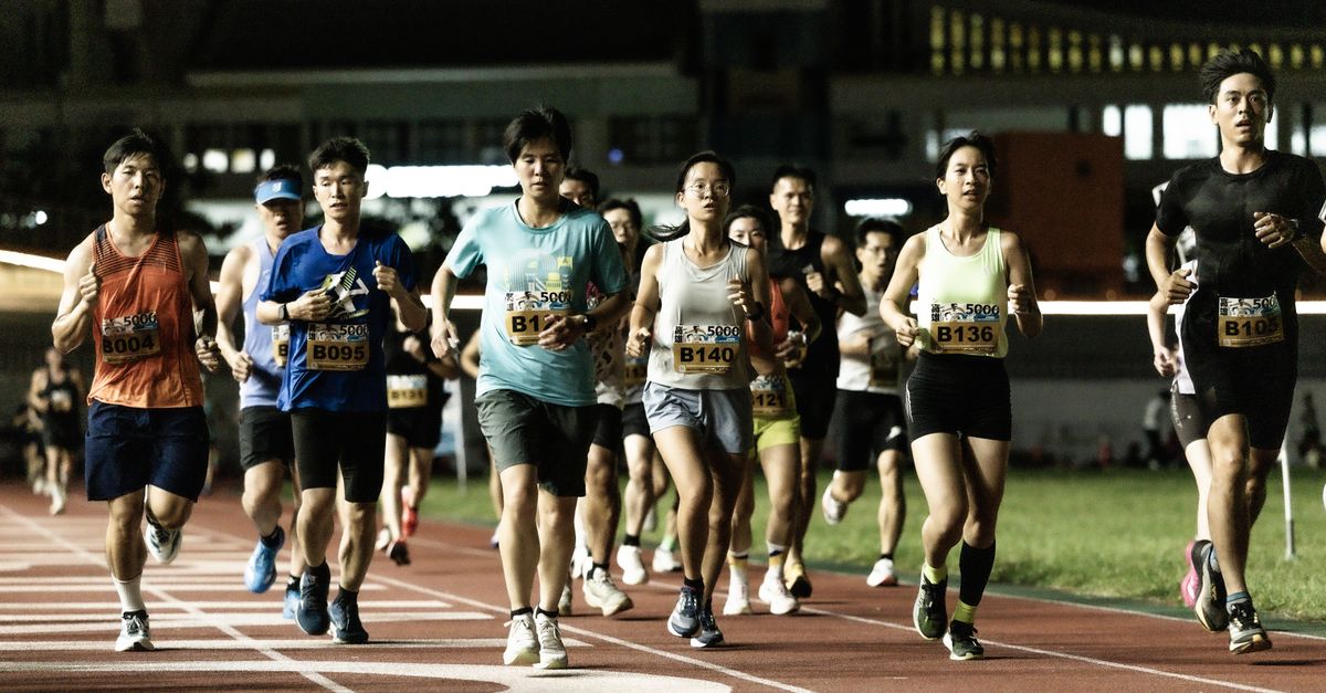 A diverse group of runners participating in a nighttime marathon on an illuminated track.